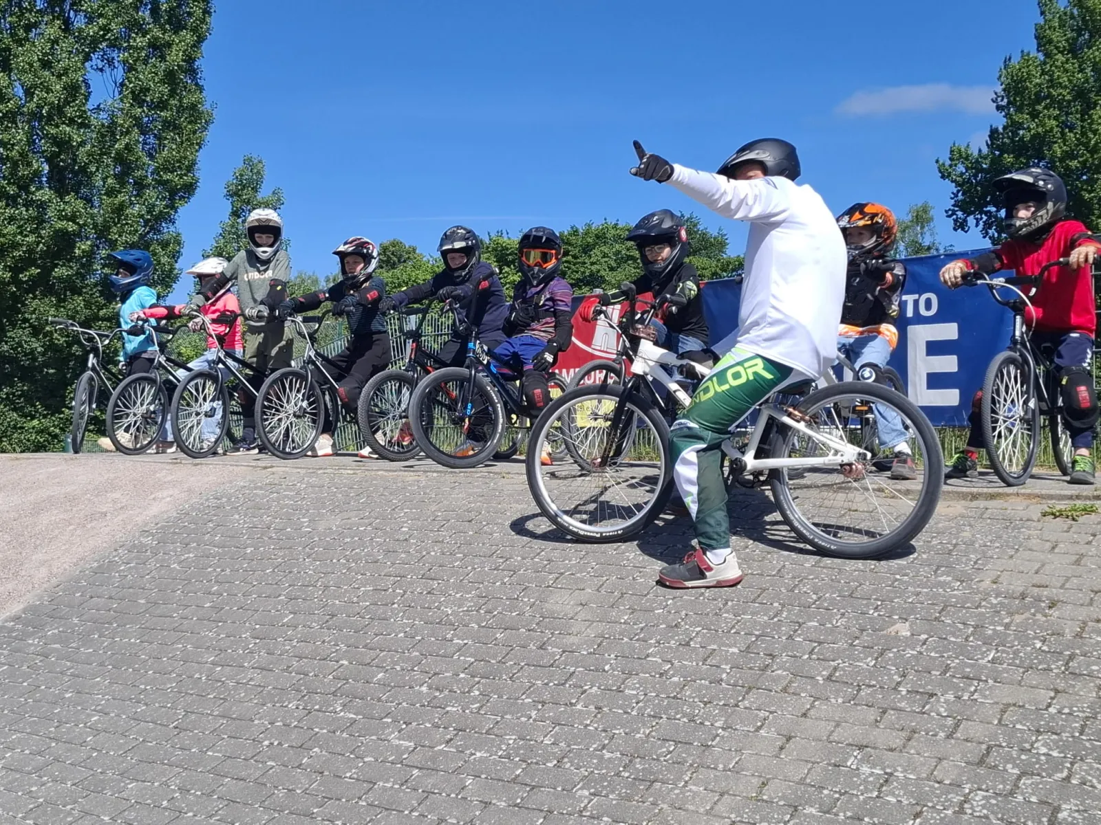 Coach gibt den Kindern vor dem Start Anweisungen auf der BMX-Bahn