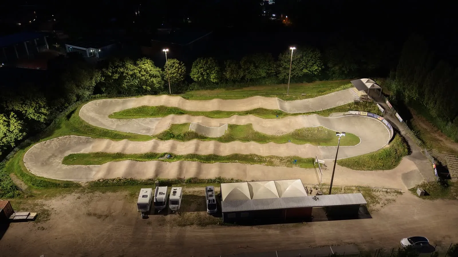 Nächtliche Luftaufnahme des hell beleuchteten BMX-Tracks im Neusurenland